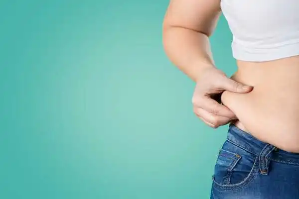 Image of woman pinching her love handles to show weight gain Earls Barton